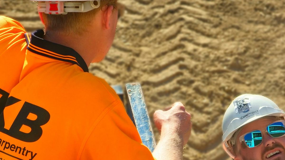 Tradespeople in hi-vis shirts on a building site